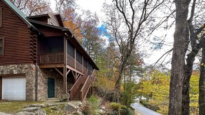 A log cabin with a stone foundation, a front porch, and a garage. - A Log Home Above the Lake | Hickory Hills Cabin (Highlands)