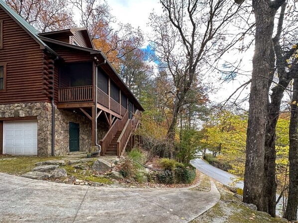 A log cabin with a stone foundation, a front porch, and a garage. - A Log Home Above the Lake | Hickory Hills Cabin (Highlands)