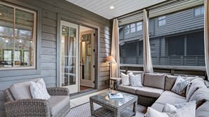 A cozy outdoor seating area with wicker furniture, a glass coffee table, and a lamp.