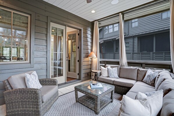 A cozy outdoor seating area with wicker furniture, a glass coffee table, and a lamp.