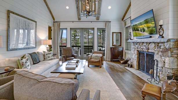 A spacious living room with a stone fireplace, a large painting, and a cozy seating area with a sofa and armchairs.