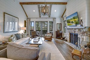 A spacious living room with a stone fireplace, a large painting, and a cozy seating area with a sofa and armchairs.
