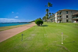 Um campo de golfe com vista clara para o oceano, relvado bem cuidado e um edifício com várias varandas.