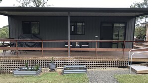 A modern house with a wooden deck, outdoor seating, and raised garden beds. - Night retreat in the country (Paterson)
