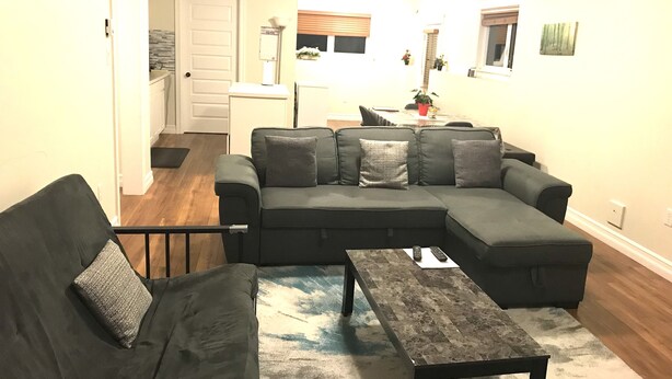 A living room with a sectional sofa, a coffee table, and a dining area with a table and chairs. - Stylish 1BR unit in Bedford, only 15 min to downtown Halifax. Near shopping area (Halifax)