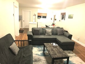 En stue med en modulsofa, et sofabord og et spiseområde med et bord og stole.