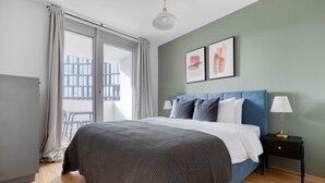 A modern bedroom with a large bed, a nightstand with a lamp, and a view of the outside balcony. - Amazing Belview 1BR w/ Gym, Lounge & Elevator, nr Metro, by Blueground (Vienna)