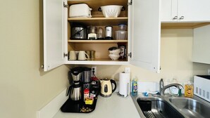 A compact kitchen with white cabinets, a sink, and various appliances including a coffee maker and a kettle. - Far East Escape: Zen apartment, Japanese tea table (Salem)
