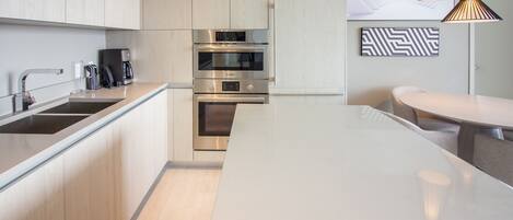 A modern kitchen with stainless steel appliances, a built-in oven, and a large island.