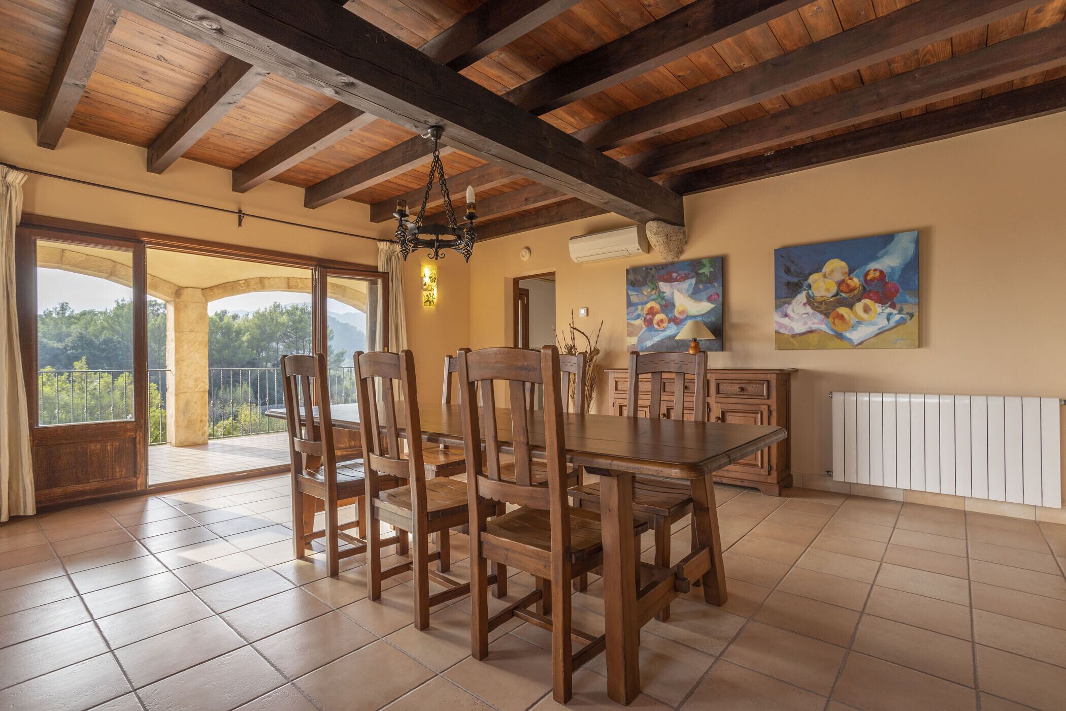 Un comedor con muebles de madera, una araña y obras de arte en las paredes.