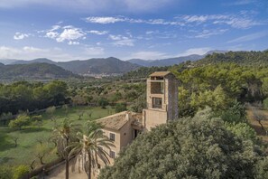 A stone tower with a balcony, surrounded by lush greenery and mountains in the background. - 6 bedroom finca with pool and barbecue (Selva)