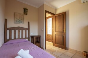 A bedroom with a wooden bed, a nightstand, a door, and a wall-mounted painting. - 6 bedroom finca with pool and barbecue (Selva)
