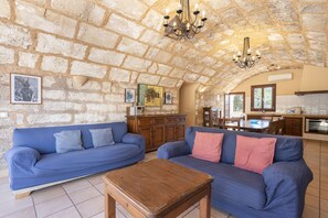 A spacious living area with stone walls, a wooden dining table, and two sofas. - 6 bedroom finca with pool and barbecue (Selva)