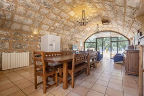 A spacious kitchen with stone walls, wooden furniture, and large windows.