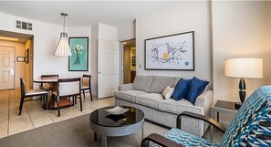 Relax in this stylish living room with a round coffee table, sofa, dining area, and abstract art.