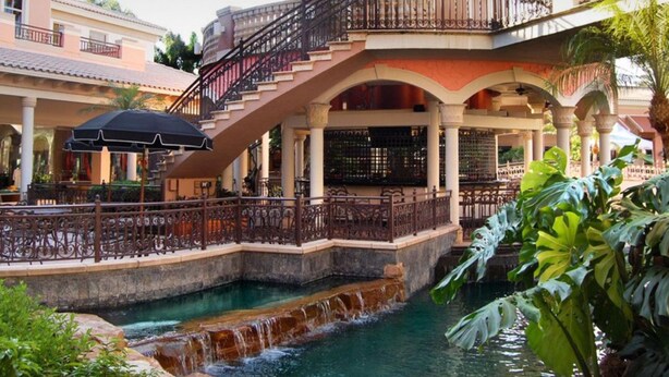 A hotel with a water feature, outdoor seating, and a staircase connecting different levels. - Mid Century Home with Heated Pool + Spa (Bonita Springs)