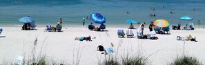 A beach with people sunbathing, umbrellas, and beach chairs.