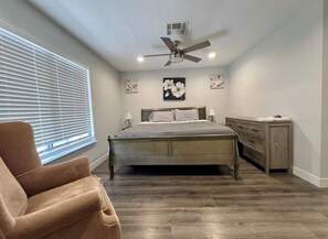 Relax in this serene bedroom with a large bed, bedside tables, and a ceiling fan.