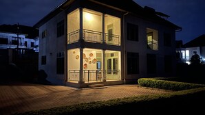Ein zweistöckiges Haus mit Balkon, einer gut beleuchteten Eingangspartei und einem gepflasterten Auffahrt.