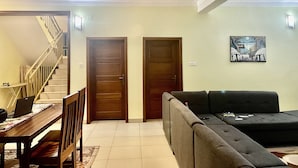 Ein Wohnzimmer mit Sofa, einem Esstisch mit Stühlen, einer Treppe und einem Deckenventilator.