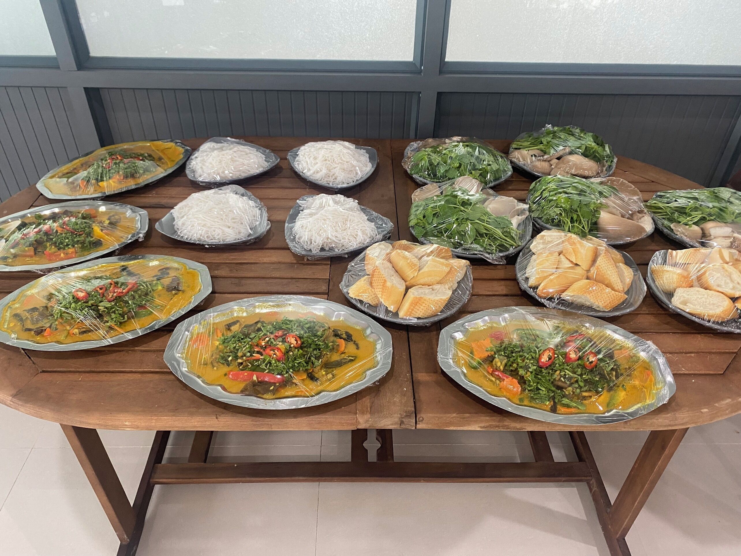 Una mesa con diversos alimentos, como arroz, fideos, verduras y pan.