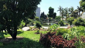 Un jardín con un estanque, un puente y diversas plantas.
