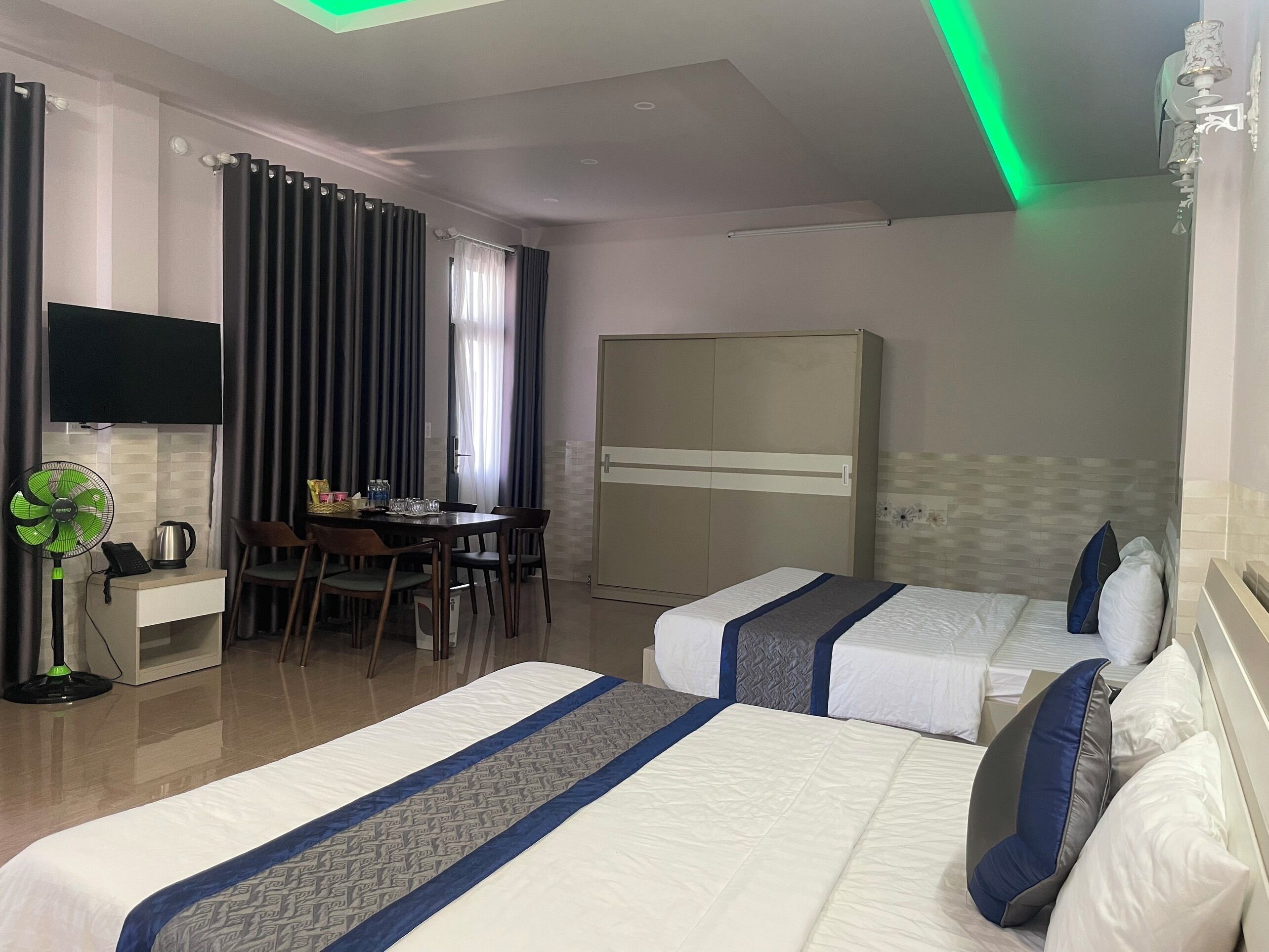 Een hotelkamer met twee bedden, een bureau met stoel, een kledingkast en een aan de muur bevestigde televisie.