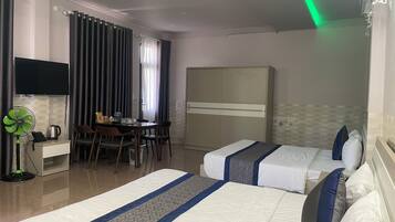 Een hotelkamer met twee bedden, een bureau met stoel, een kledingkast en een aan de muur bevestigde televisie.