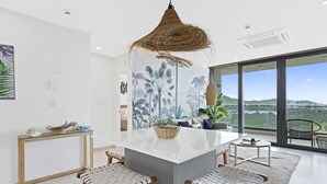 A modern kitchen with a central island, bar stools, and a large window offering a scenic view. - A-1003 Stunning one bedroom apartment (Cupecoy)