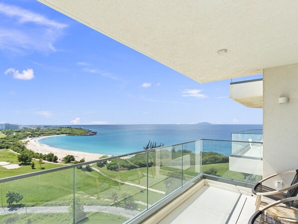 A balcony with a clear view of a beach and ocean.