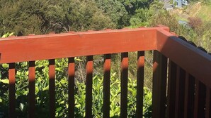 Une vue sur la côte, avec une balustrade en bois, une végétation luxuriante et une plage.