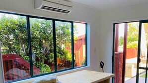 Une pièce avec une grande fenêtre, une table en bois, une chaise blanche et un tapis moelleux.