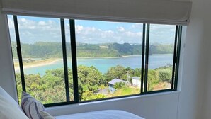 Une chambre dotée d’une grande fenêtre donnant sur un lac et une végétation luxuriante.