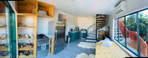 Kitchen features a stove, stainless steel refrigerator, and wooden shelf unit.