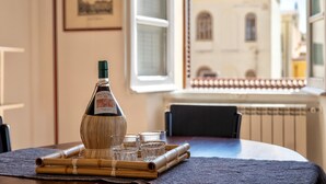 A bottle of wine, a glass, and a bamboo mat on a table with a view of a building through a window. - Liberty 13 in Sassari (Sassari)