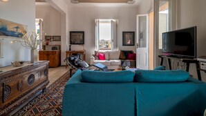 A living room with a sofa, a television, and a patterned rug. - Liberty 13 in Sassari (Sassari)