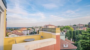 Eine Dachterrasse mit Tisch und Stühlen, mit Blick auf ein Wohngebiet mit verschiedenen Gebäuden und Bäumen.