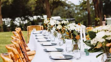 A long table set outdoors with chairs, white tablecloth, and floral centerpieces.