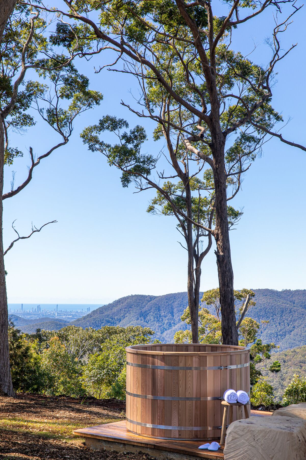 Tinaja de madera con toallas, rodeada de árboles y una vista del horizonte de la ciudad.