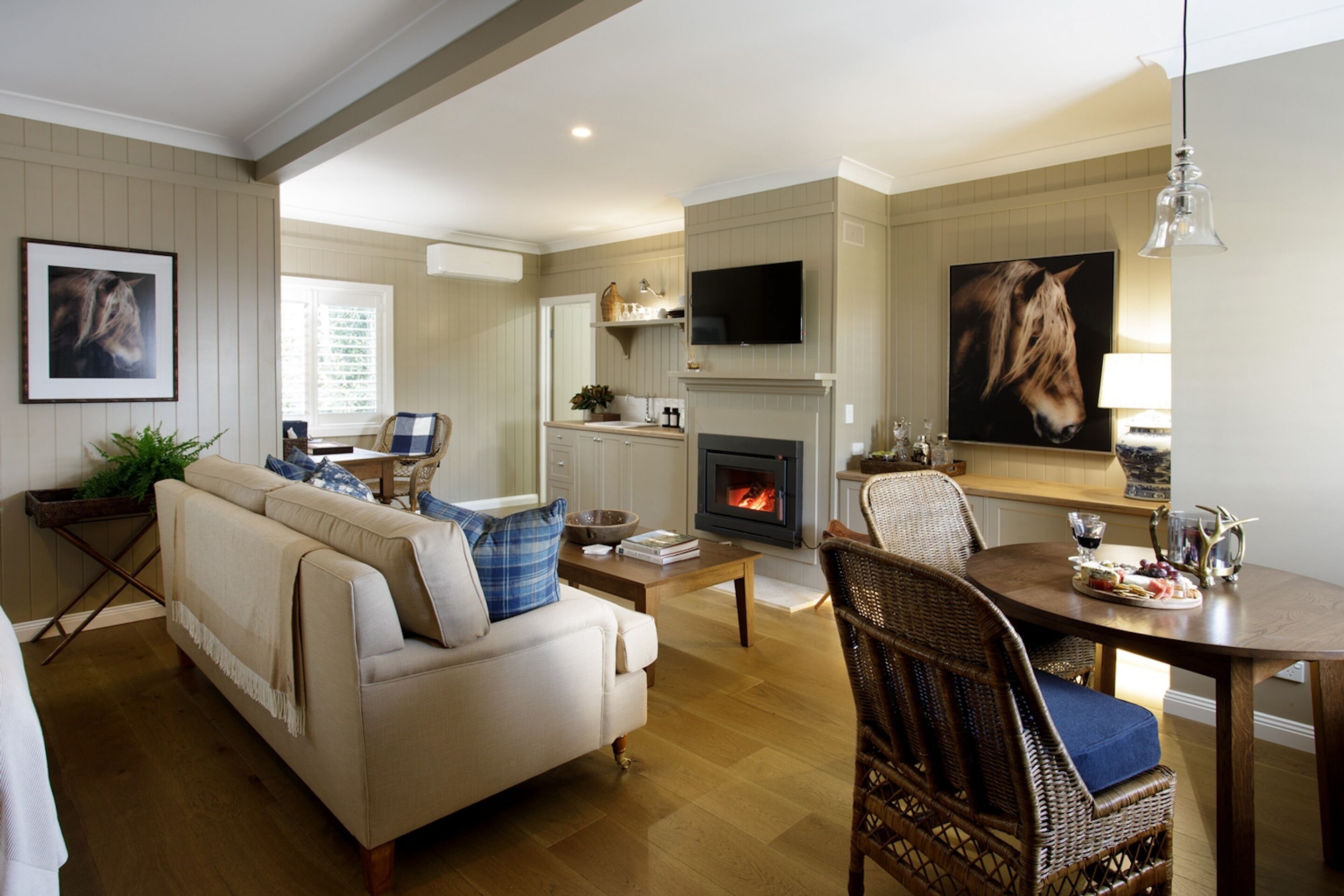 Una sala de estar acogedora con chimenea, un televisor y un comedor con mesa puesta para una comida.