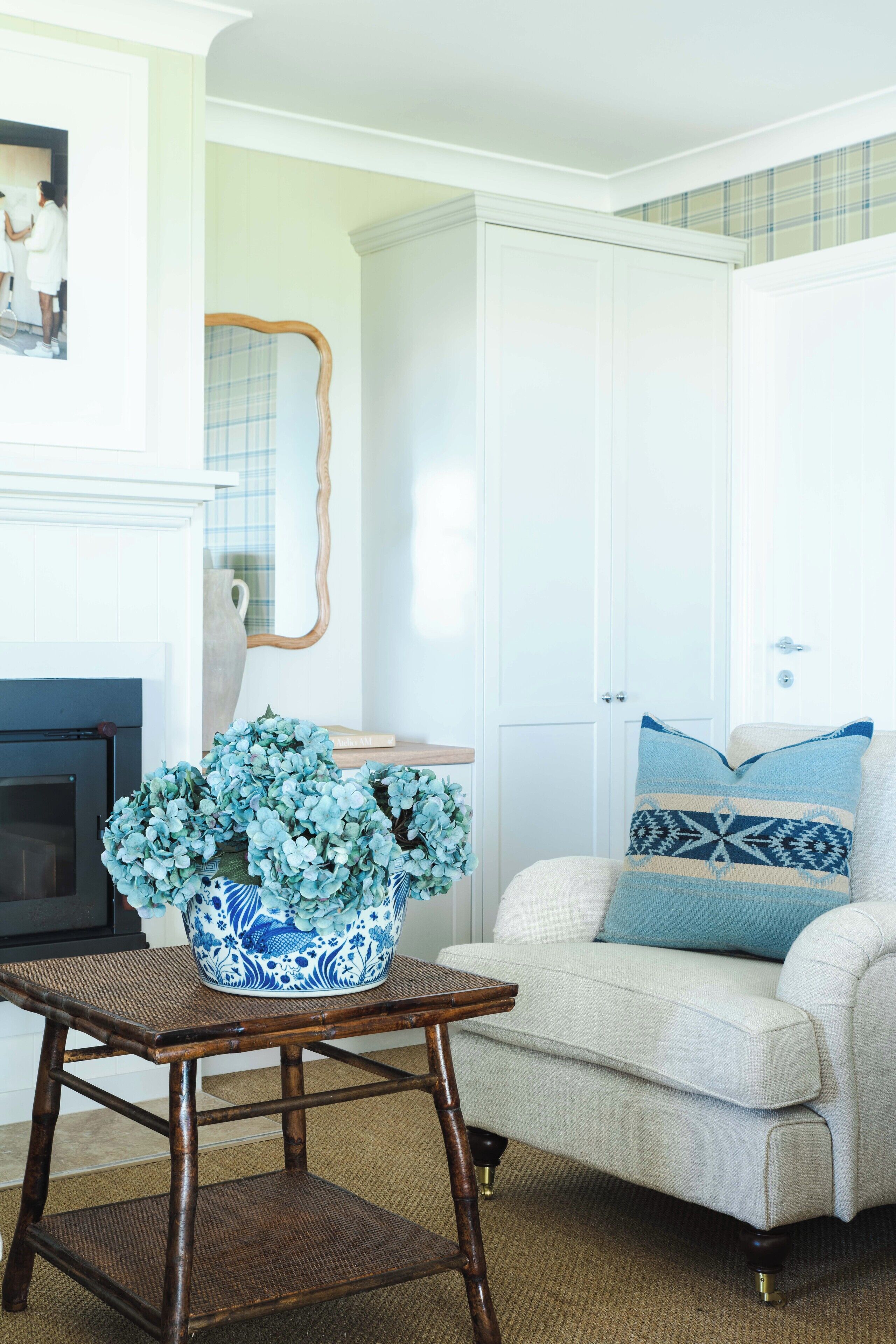 A living room with a sofa, a table with a vase of flowers, a fireplace, and a door with a mirror.