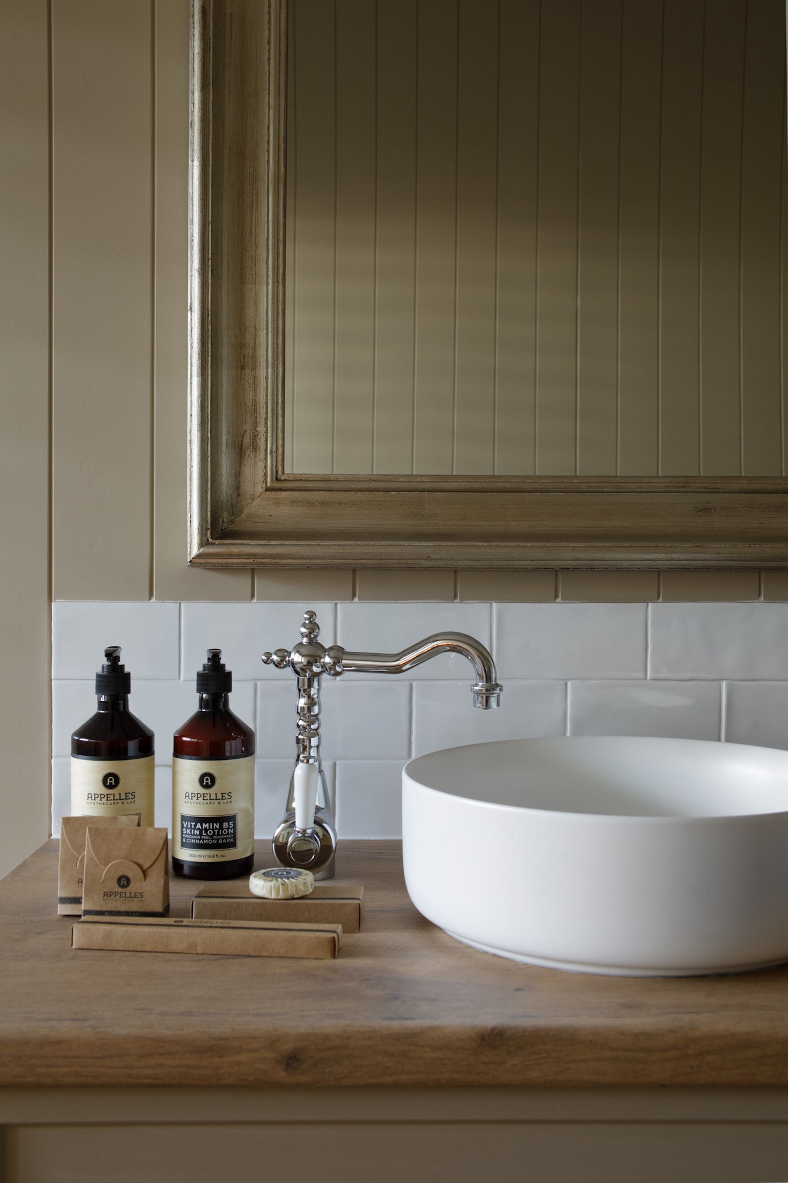 A bathroom with a white sink, wooden countertop, and two bottles of skin lotion.