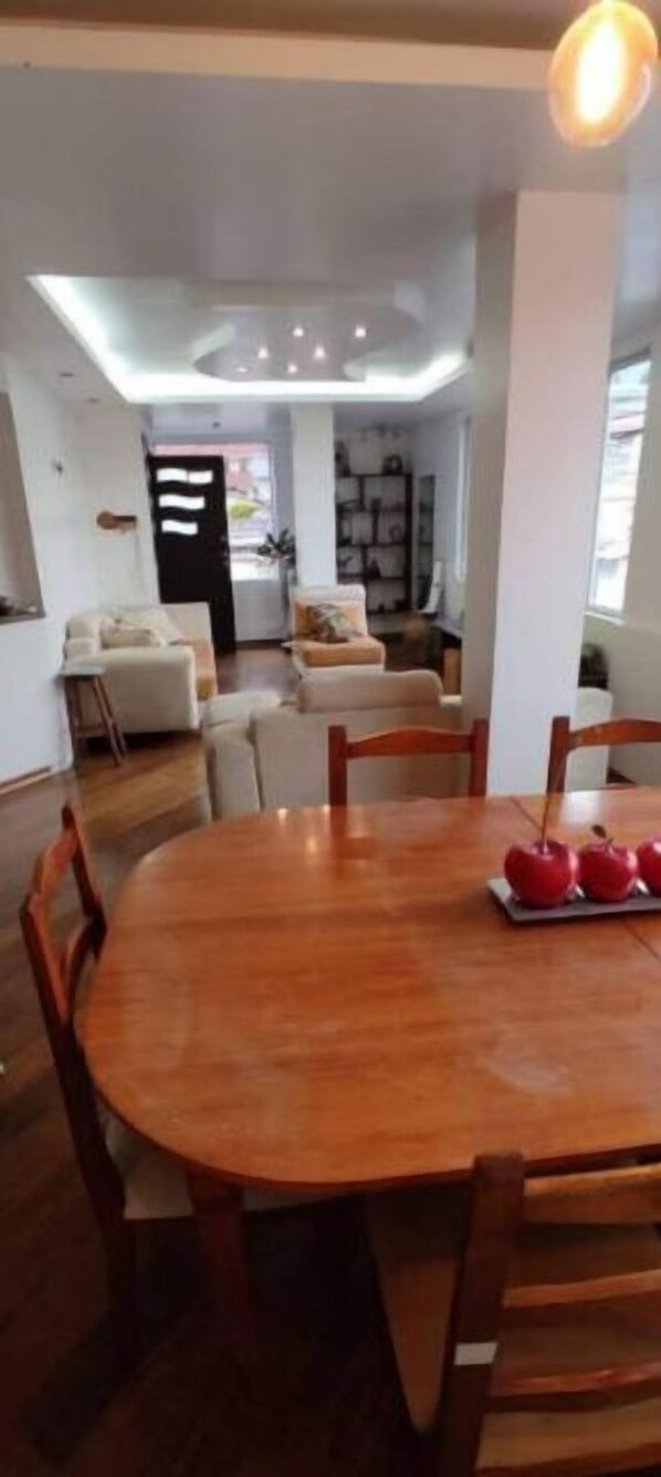 A modern dining area with a wooden table and chairs, a black-framed mirror, and a bookshelf in the background. - Quito - Conocoto apartment Ideal for resting king size bed (Quito)