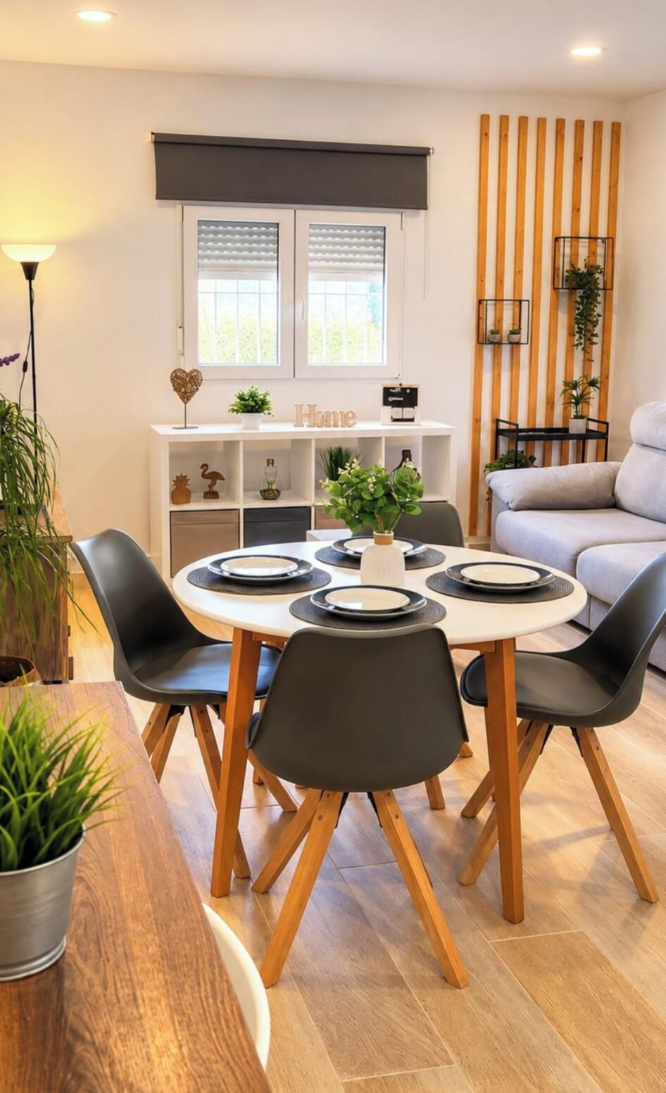 Un coin repas avec une table ronde, des chaises noires et un meuble blanc agrémenté d’objets décoratifs.