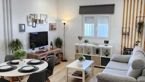 A modern living room with a dining area, a sofa, and a TV. - Minichalet Jacaranda with swimming pool, garden and barbecue. (Chiclana)