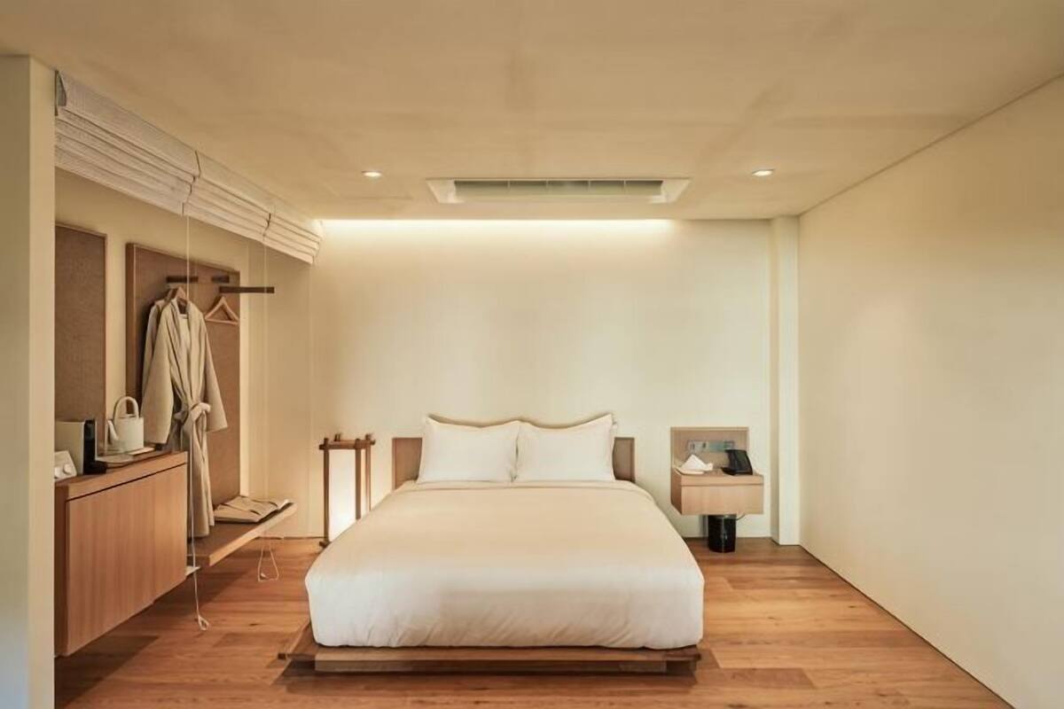 Une chambre avec un grand lit, des tables de chevet, une armoire et un porte-manteau.