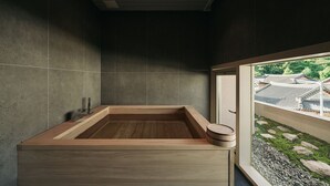 A modern bathroom with a wooden bathtub, tiled walls, and a view of traditional architecture through a window. - IJE Gyeongju (Gyeongju)