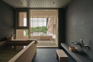 Une salle de bain moderne avec un banc en bois, une baignoire et une fenêtre donnant sur un paysage verdoyant.