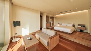 A modern hotel room with a wooden floor, a sofa, a bed, a bedside table, and a small desk with a lamp. - IJE Gyeongju (Gyeongju)
