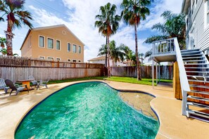 A backyard with a swimming pool, a wooden deck, and a house with a fenced yard. - Sophisticated, bay-view home with pool, deck, W/D, grill & AC - close to beach (South Padre Island)